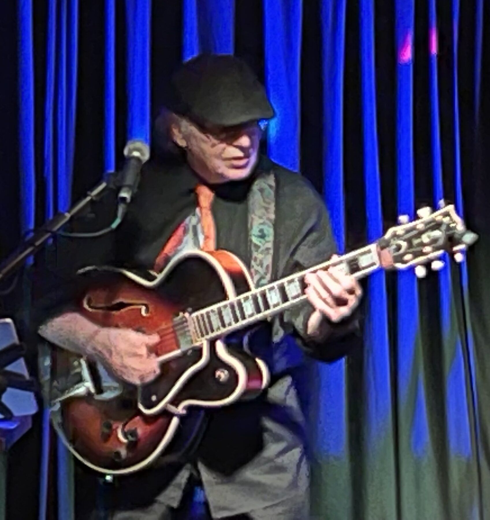 Philly Joe playing archtop on a blue-lit stage